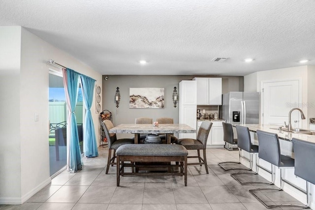 tiled dining room featuring a textured ceiling and sink