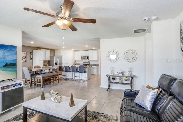 tiled living room with a textured ceiling and ceiling fan