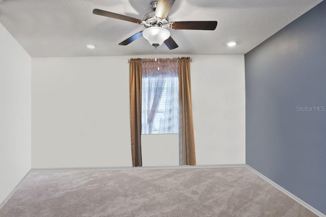 carpeted empty room with ceiling fan and a textured ceiling