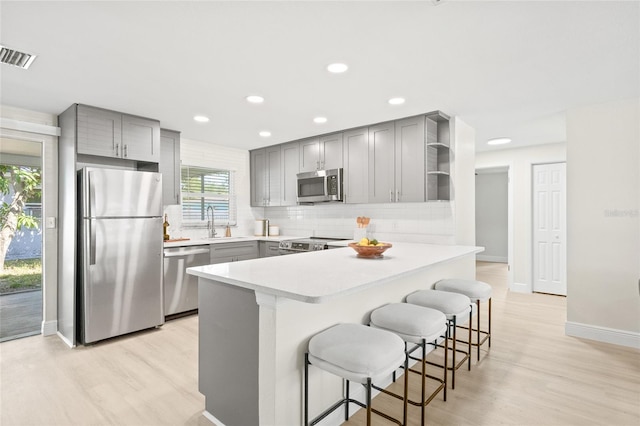 kitchen featuring appliances with stainless steel finishes, light hardwood / wood-style flooring, a kitchen bar, and plenty of natural light