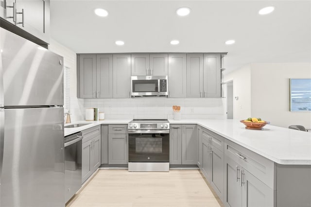 kitchen featuring gray cabinets, stainless steel appliances, and light hardwood / wood-style floors