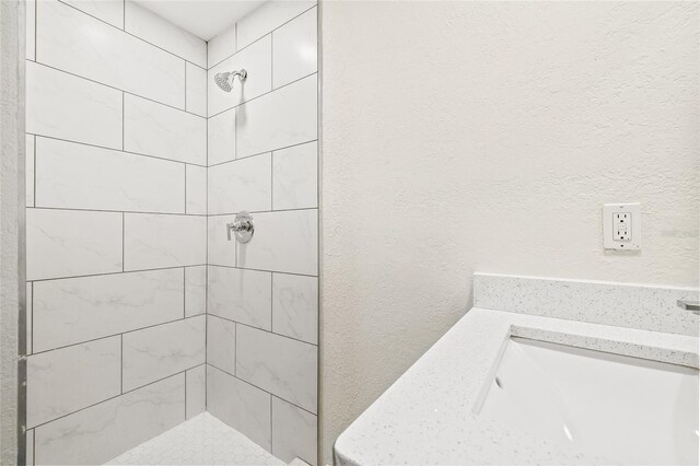 bathroom featuring a tile shower and sink