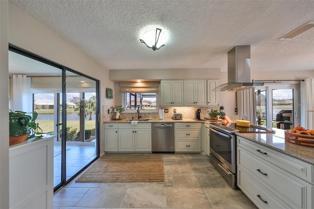 kitchen featuring appliances with stainless steel finishes, island range hood, white cabinetry, and sink