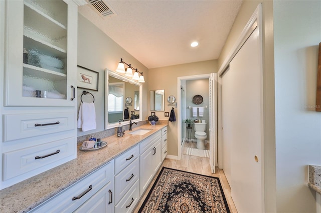 bathroom featuring vanity, a textured ceiling, and toilet