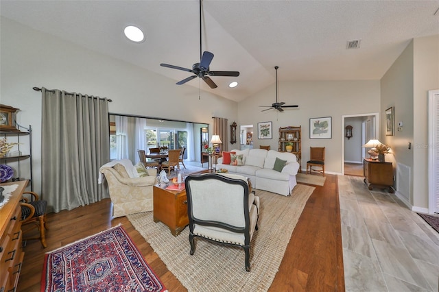 living room with ceiling fan, vaulted ceiling, and light wood-type flooring