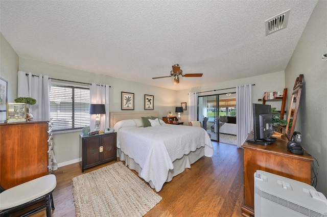 bedroom with ceiling fan, dark hardwood / wood-style flooring, a textured ceiling, and access to outside