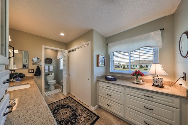 bathroom featuring vanity, a textured ceiling, toilet, and tile patterned flooring