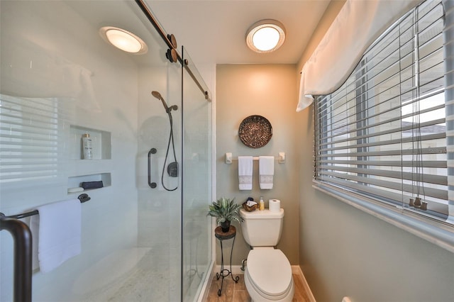 bathroom featuring a shower with door and toilet