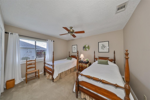 carpeted bedroom with ceiling fan and a textured ceiling