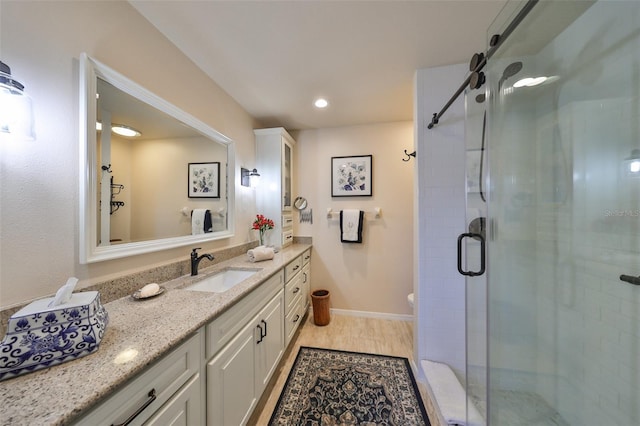 bathroom with a shower with door, vanity, and wood-type flooring