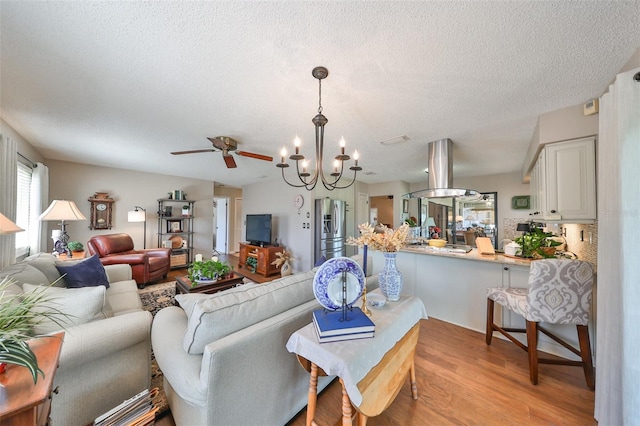 living room with a textured ceiling, ceiling fan with notable chandelier, and light wood-type flooring