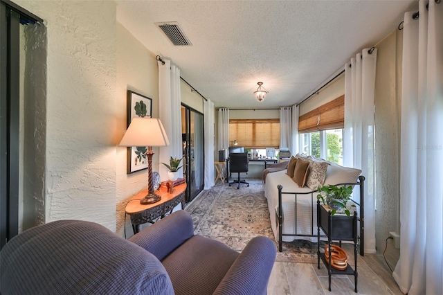 living room with light wood-type flooring and a textured ceiling