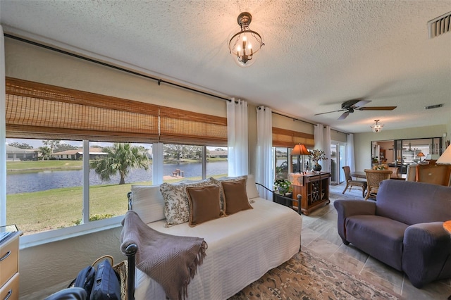 sunroom with ceiling fan with notable chandelier and a water view