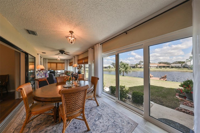 sunroom with a water view and ceiling fan