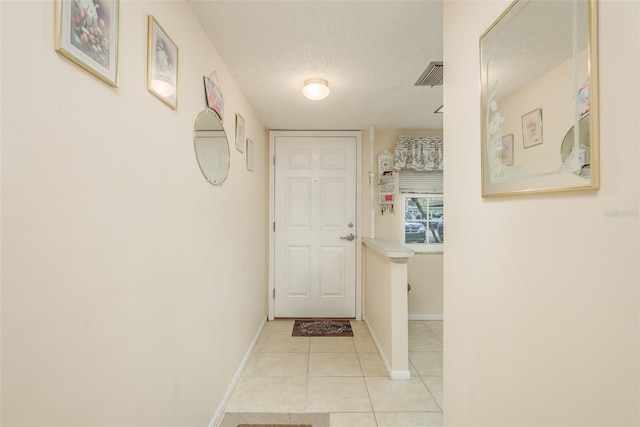 hallway with a textured ceiling and light tile patterned floors