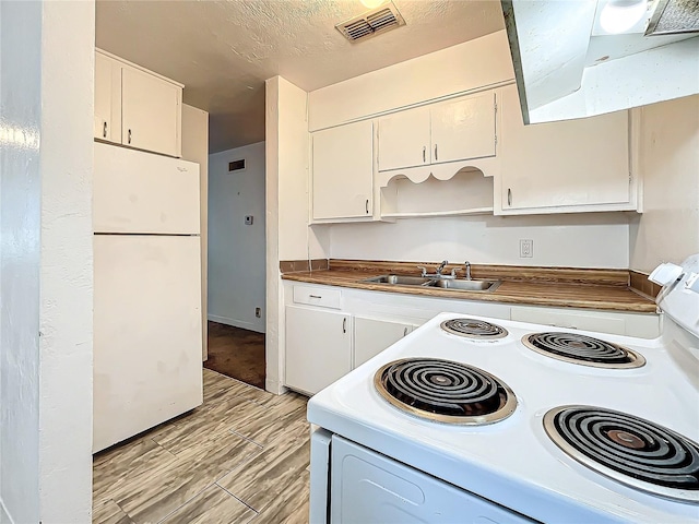 kitchen featuring sink, white cabinets, white appliances, and light hardwood / wood-style floors