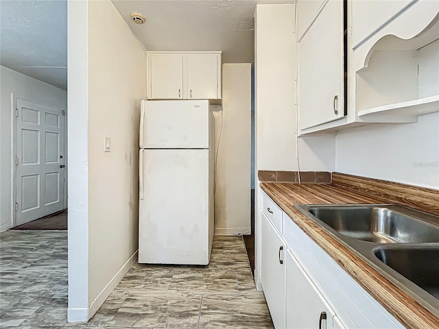 kitchen with white cabinetry, sink, and white refrigerator