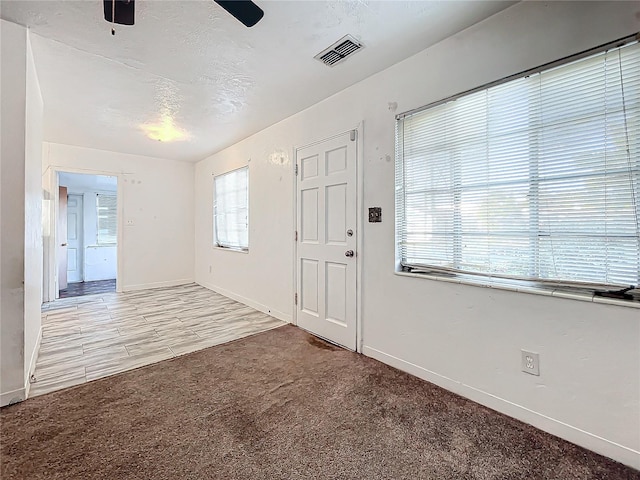 carpeted foyer with ceiling fan and a textured ceiling