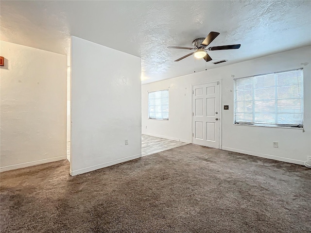 interior space with ceiling fan, a wealth of natural light, and dark colored carpet