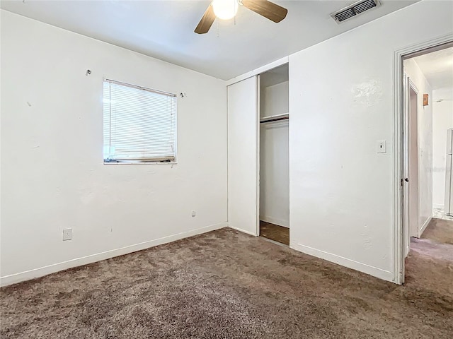 unfurnished bedroom featuring dark colored carpet, a closet, and ceiling fan