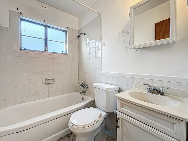 full bathroom featuring tiled shower / bath, vanity, toilet, and tile walls