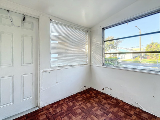 spare room with dark parquet floors and vaulted ceiling