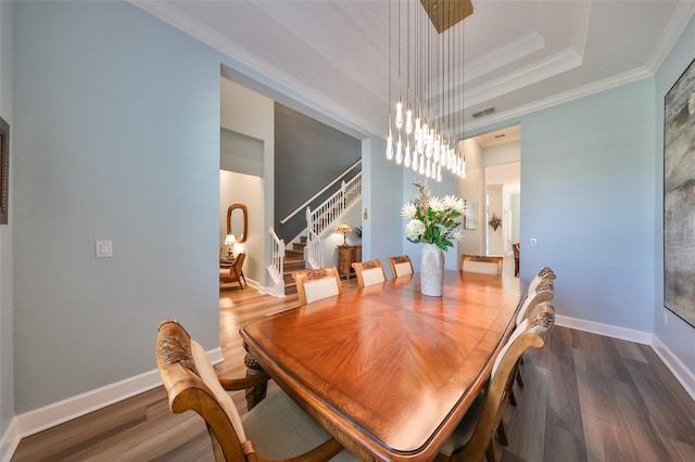 dining area with crown molding, dark hardwood / wood-style floors, and a raised ceiling