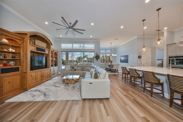 living room featuring ornamental molding, ceiling fan with notable chandelier, and light wood-type flooring