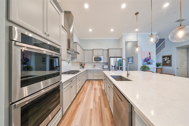 kitchen with light hardwood / wood-style flooring, stainless steel appliances, hanging light fixtures, and sink