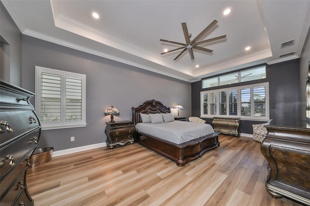 bedroom with ceiling fan, a tray ceiling, light hardwood / wood-style flooring, and crown molding