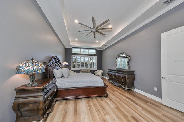 bedroom with crown molding, hardwood / wood-style flooring, and a tray ceiling