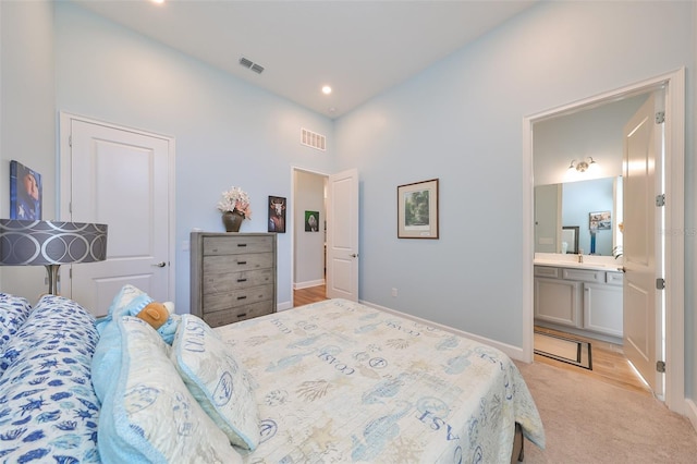 bedroom featuring ensuite bath and light colored carpet