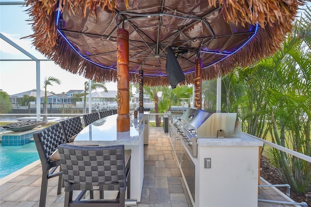 view of patio / terrace featuring an outdoor bar, a lanai, area for grilling, and exterior kitchen