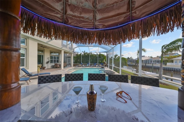 view of pool with a water view, a patio area, a lanai, and ceiling fan