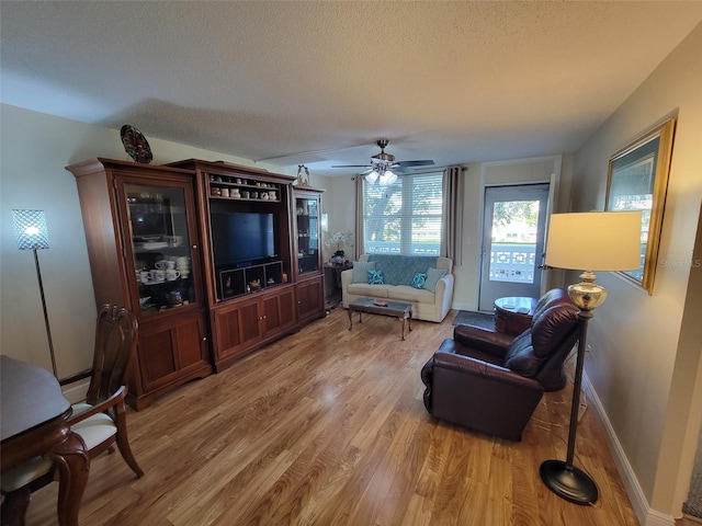 living room with a textured ceiling, hardwood / wood-style flooring, and ceiling fan