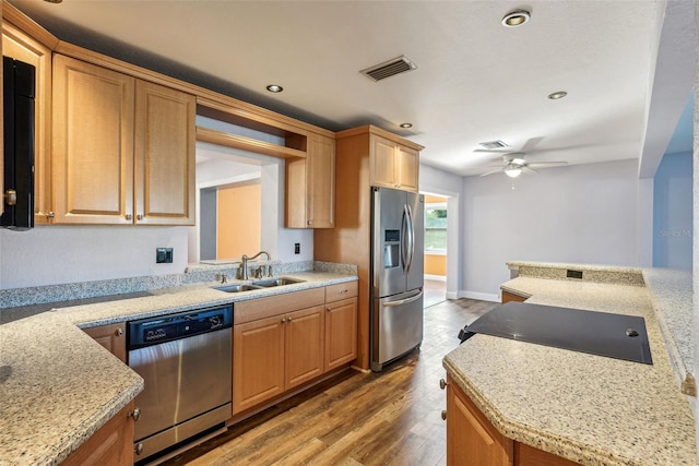 kitchen with light stone countertops, stainless steel appliances, ceiling fan, sink, and hardwood / wood-style floors