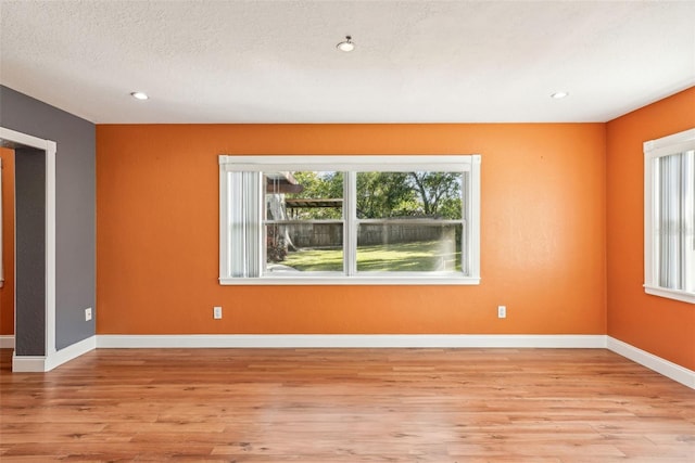 spare room featuring a textured ceiling and light hardwood / wood-style flooring