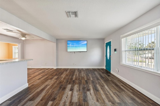 unfurnished living room with dark hardwood / wood-style flooring and ceiling fan