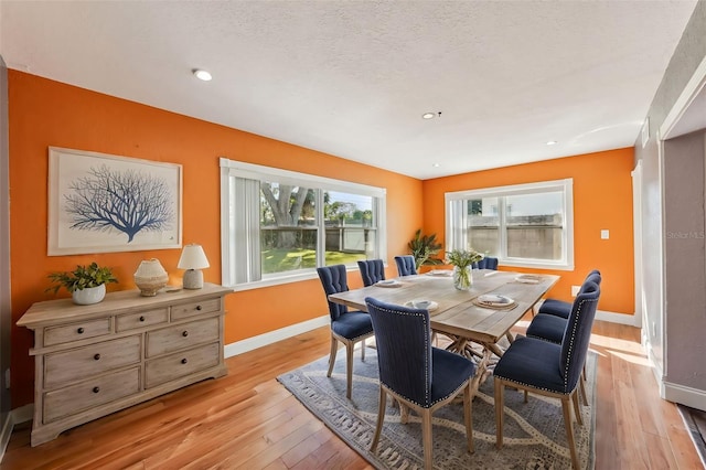 dining room featuring a textured ceiling, light hardwood / wood-style flooring, and a wealth of natural light