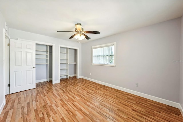 unfurnished bedroom with ceiling fan, two closets, and light wood-type flooring