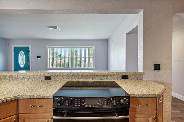 kitchen featuring dark hardwood / wood-style floors, black stove, kitchen peninsula, and light stone counters