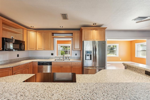 kitchen with light stone countertops, sink, stainless steel appliances, and a textured ceiling