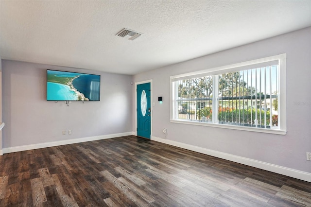 unfurnished room featuring dark hardwood / wood-style flooring, a textured ceiling, and a wealth of natural light