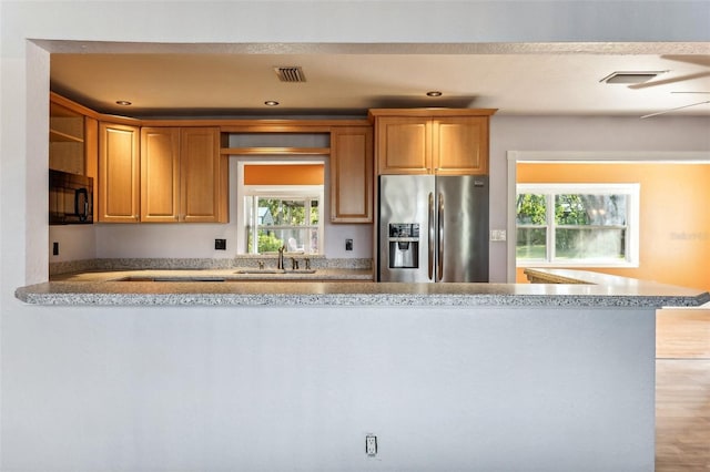 kitchen with kitchen peninsula, stainless steel refrigerator with ice dispenser, light wood-type flooring, and sink