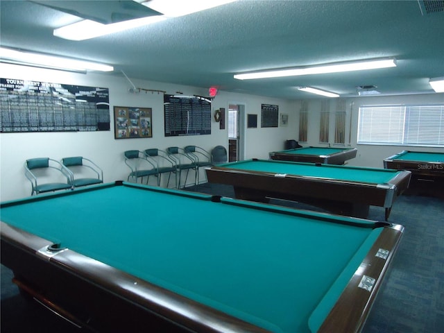 game room with pool table, a textured ceiling, and dark colored carpet