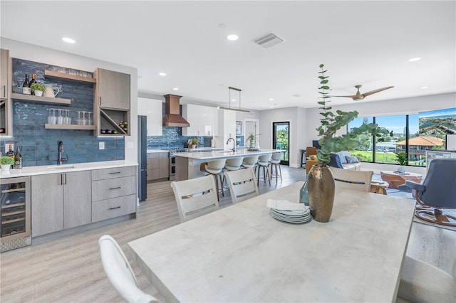 dining area featuring wine cooler, sink, light hardwood / wood-style flooring, and ceiling fan