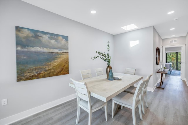 dining room featuring hardwood / wood-style flooring and a skylight