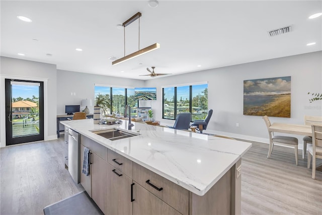 kitchen featuring a wealth of natural light, a large island, light stone countertops, and hanging light fixtures