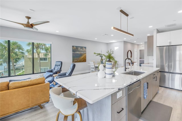 kitchen with white cabinetry, appliances with stainless steel finishes, pendant lighting, and a kitchen island with sink