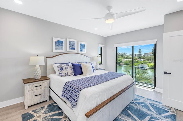 bedroom with access to outside, a water view, light hardwood / wood-style floors, and ceiling fan